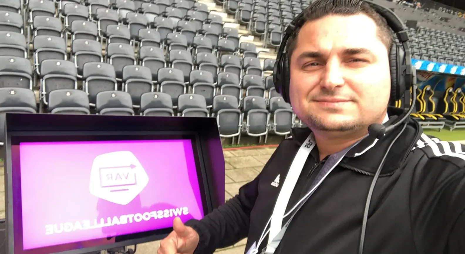 Lulzim Selimi mit Headset vor dem VAR-Bildschirm am Spielfeldrand
